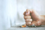 man crushing cigarette on table with fist