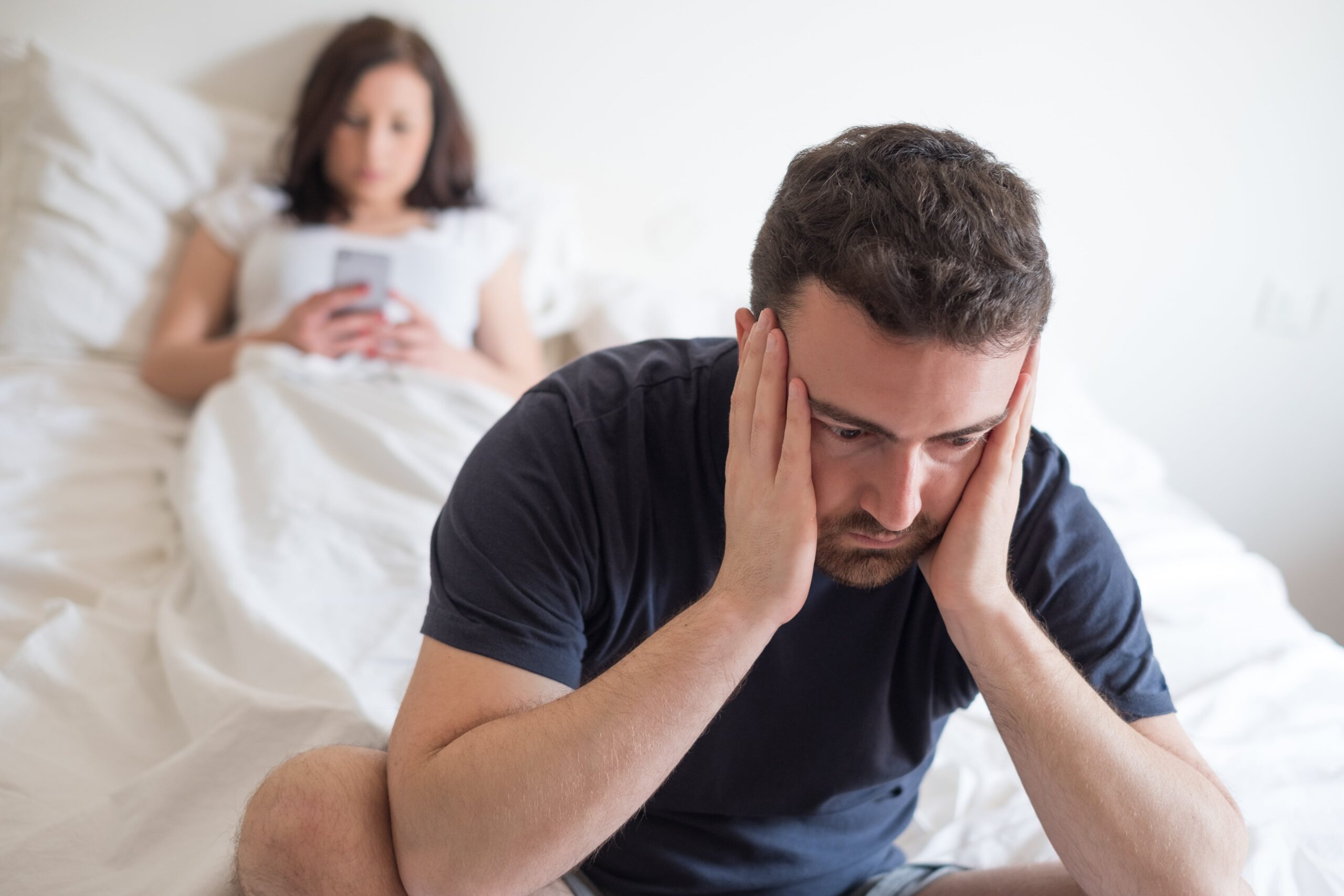 man sitting on bed with head in hands