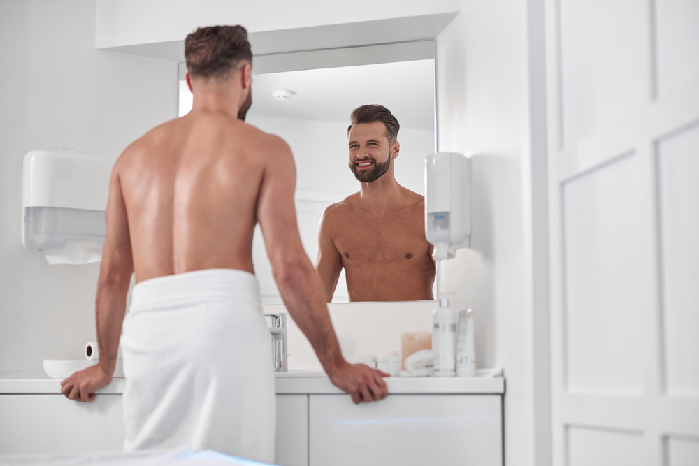 man looking at himself in the mirror, wrapped in a towel