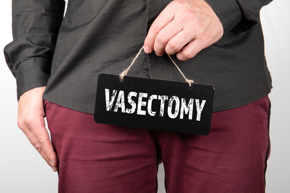 man holding sign that says vasectomy.